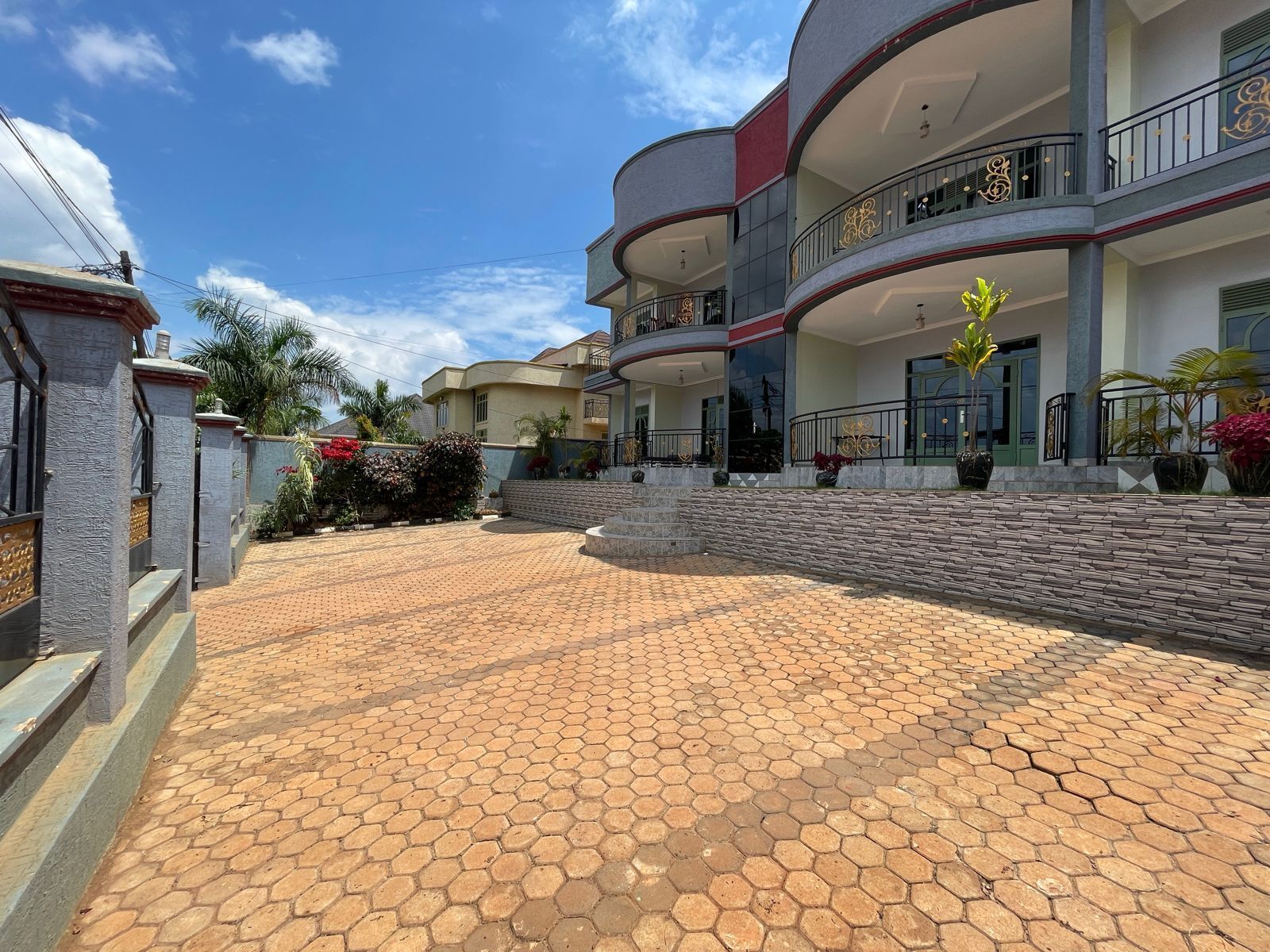 Un edificio de varios pisos con fachada curva, un patio central con pavimento hexagonal y balcones con barandillas decorativas.