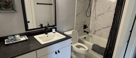 A bathroom with a white sink, a toilet, and a shower area.