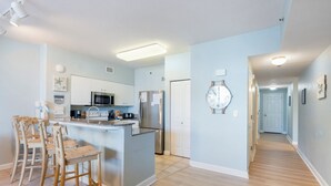 Una cocina moderna con una isla central, taburetes de bar, microondas y refrigerador.