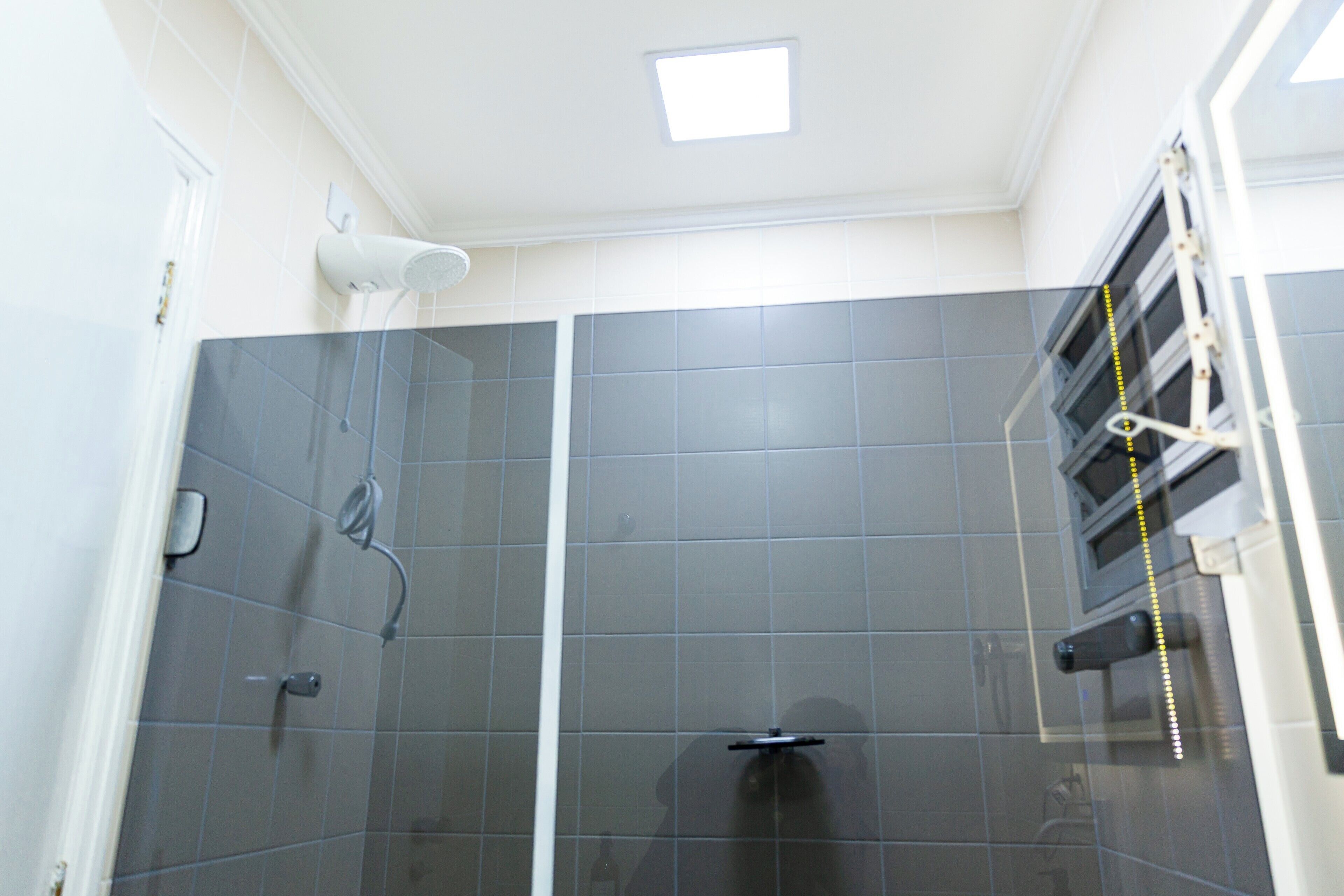 A shower area with a glass door, a handheld showerhead, and a towel rack.