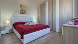 A bedroom with a bed, nightstands, a lamp, a painting, and a wooden wardrobe.