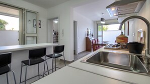 A modern kitchen with a central island, bar stools, a stainless steel sink, and a gas stove.