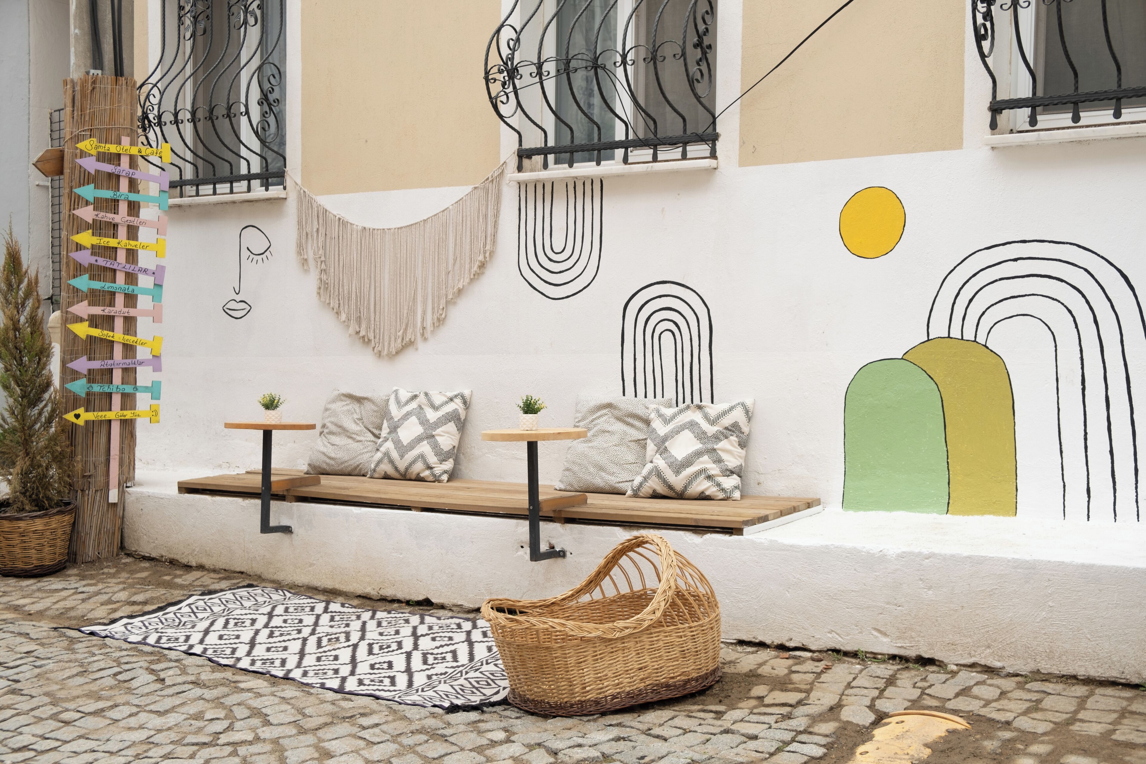 A cozy outdoor seating area with a bench, cushions, and a woven basket.