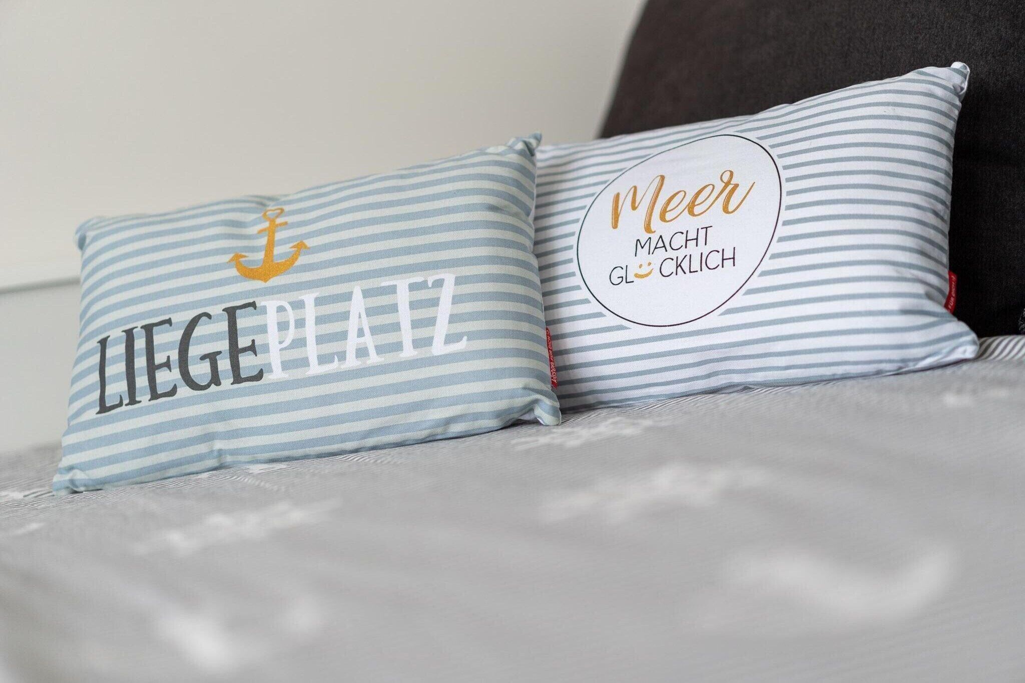 Two pillows with striped patterns and text on a bed.