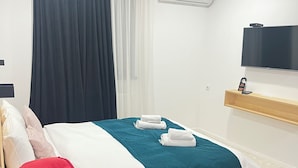 Una habitación de hotel con una cama, una silla roja, un televisor y un equipo de aire acondicionado.