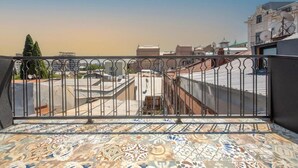 Una terraza en la azotea con suelo estampado, barandilla metálica y vistas de edificios circundantes.
