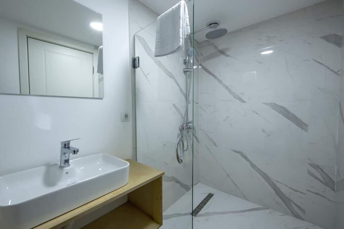 A bathroom with a white sink, a mirror, and a glass-enclosed shower area.