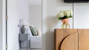 A modern bedroom with a bed, bedside table, lamp, and a wall-mounted TV.
