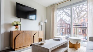 A modern living room with a flat-screen TV, a wooden cabinet, a coffee table, and a sofa.