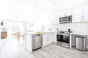 Una cocina moderna con armarios blancos, electrodomésticos de acero inoxidable y suelo de madera.