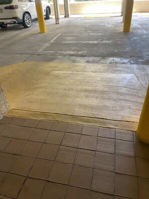 Eine Tiefgarage mit gelbem Schutzpfosten, einem weißen Auto und einem Betonboden.
