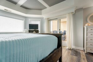 A bedroom with a bed, a television, a dresser, and a balcony with chairs. - Quiet Oceanfront Condo & Hot Tub, Steps to Coligny (Hilton Head Island)