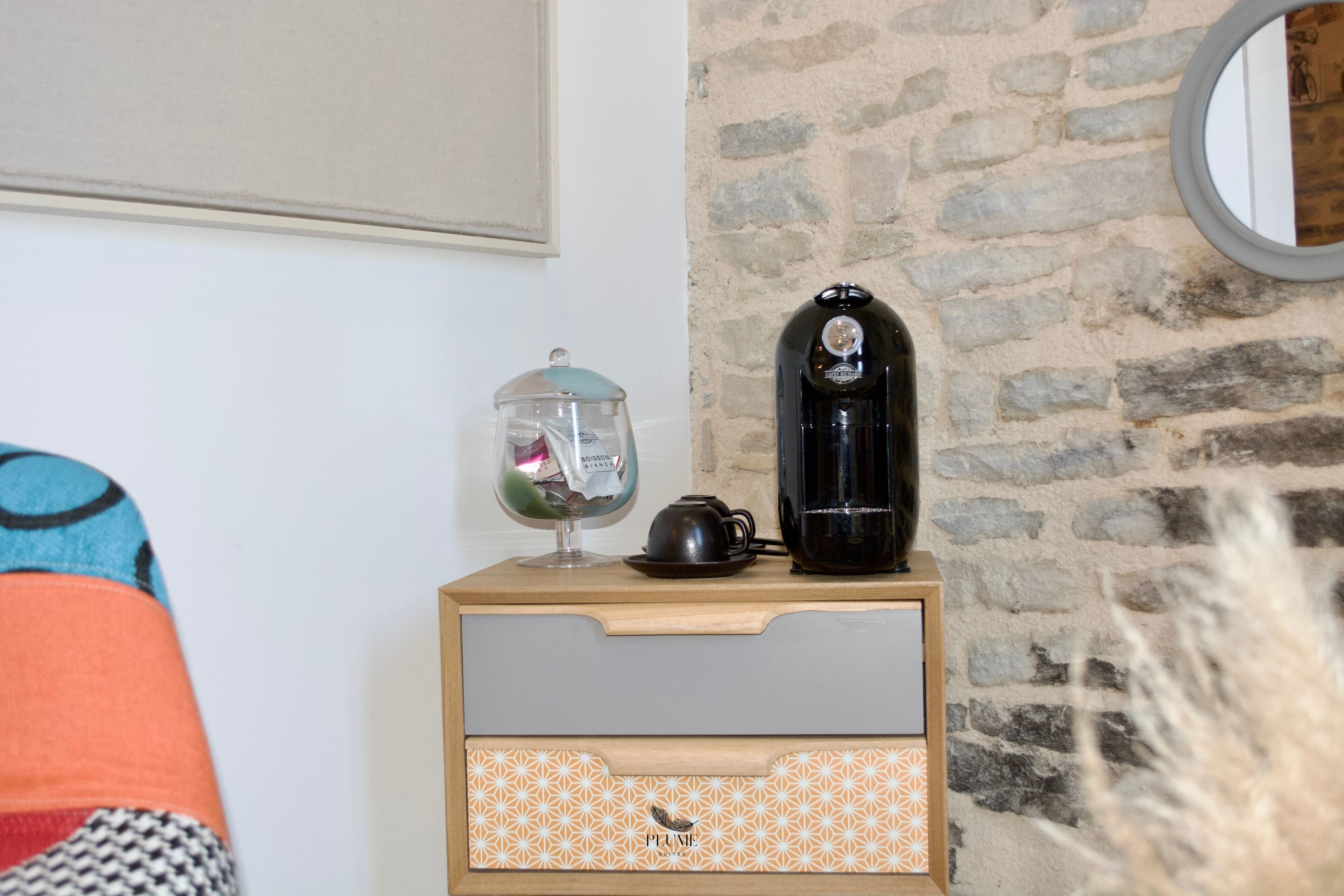 A wooden nightstand with a glass jar, a teapot, and a black electric kettle.