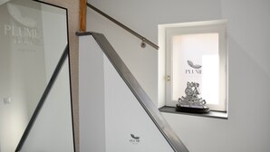 A staircase with a glass door and a window with a decorative clock. - Plume Suites (Fleurey-sur-Ouche)