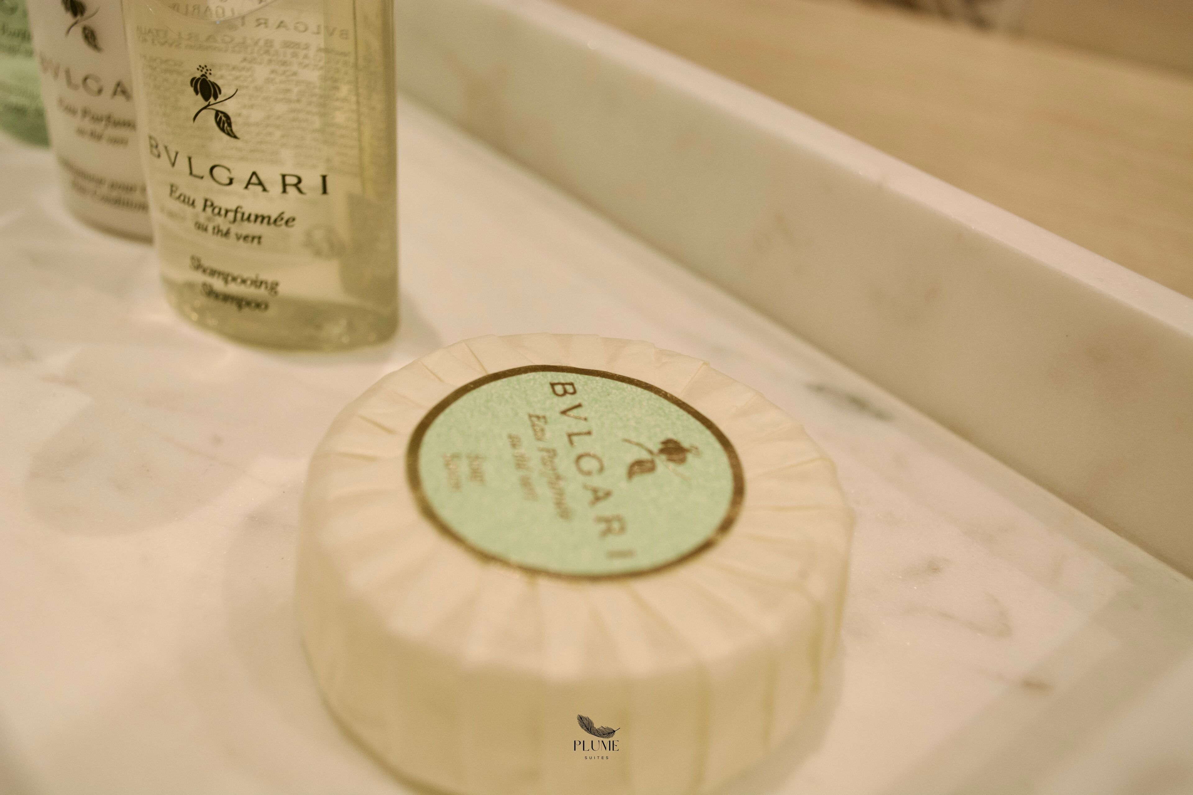 Un meuble-vasque de salle de bain avec un flacon de parfum BVLGARI et un savon.