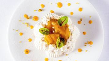 A white plate with a dessert featuring whipped cream, a caramel sauce, and mint leaves.