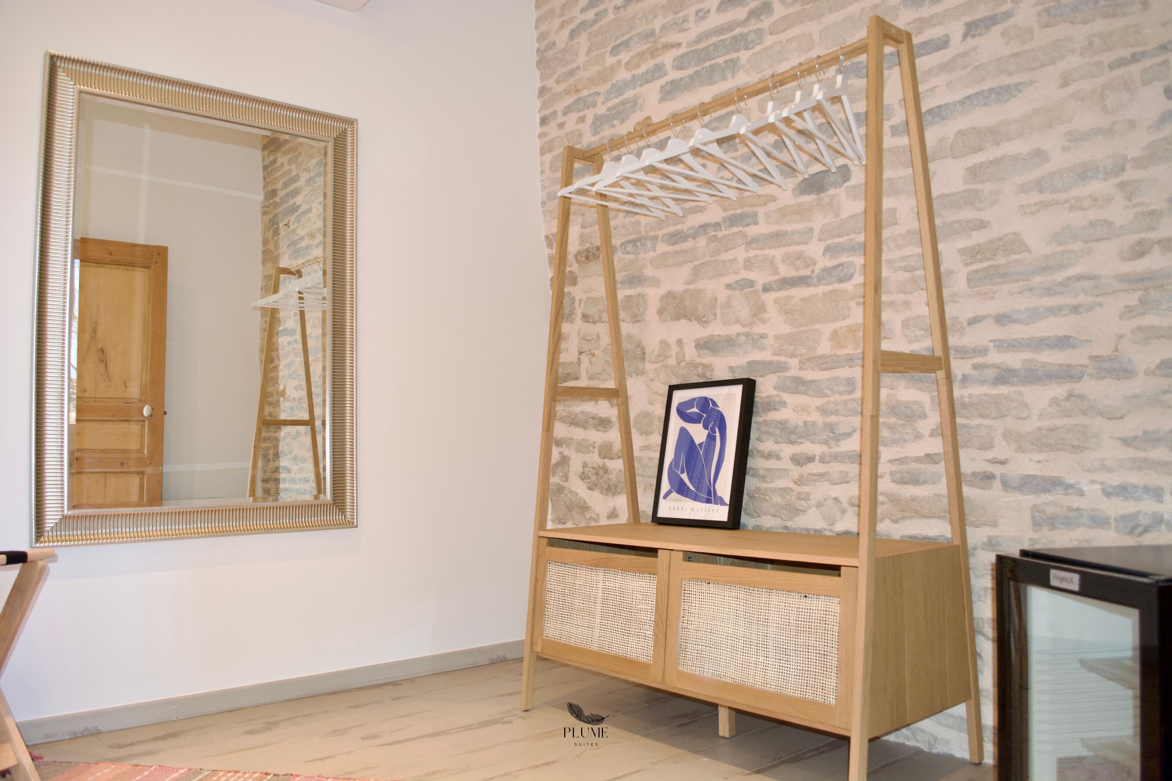 Una habitación con un espejo grande, un armario de madera con un marco de fotos y un televisor sobre un mueble.