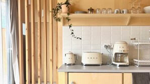 Une cuisine avec des lambris en bois, un dosseret de carreaux blancs et un plan de travail équipé d’appareils électroménagers.