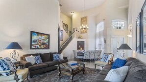 A spacious living room with a sofa set, a coffee table, and a dining area with chairs and a table.