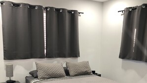 A bedroom with a bed, nightstand, lamp, and curtains.