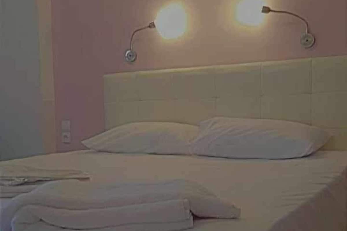 A bed with a white headboard and two wall-mounted lights.