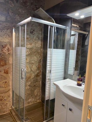 A shower with a glass door, a white sink, and a mirror above it. - Tsanis Estate  (Igoumenitsa)