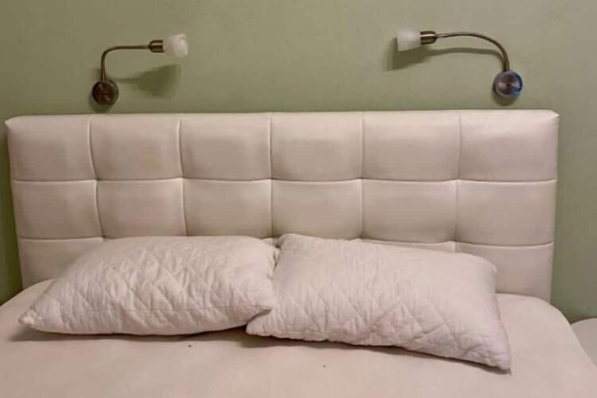 A bed with a tufted headboard, two bedside lamps, and two pillows.