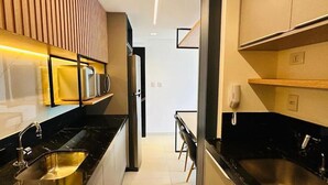 Una cocina moderna con encimeras negras, electrodomésticos de acero inoxidable y paneles de madera sobre el lavabo.