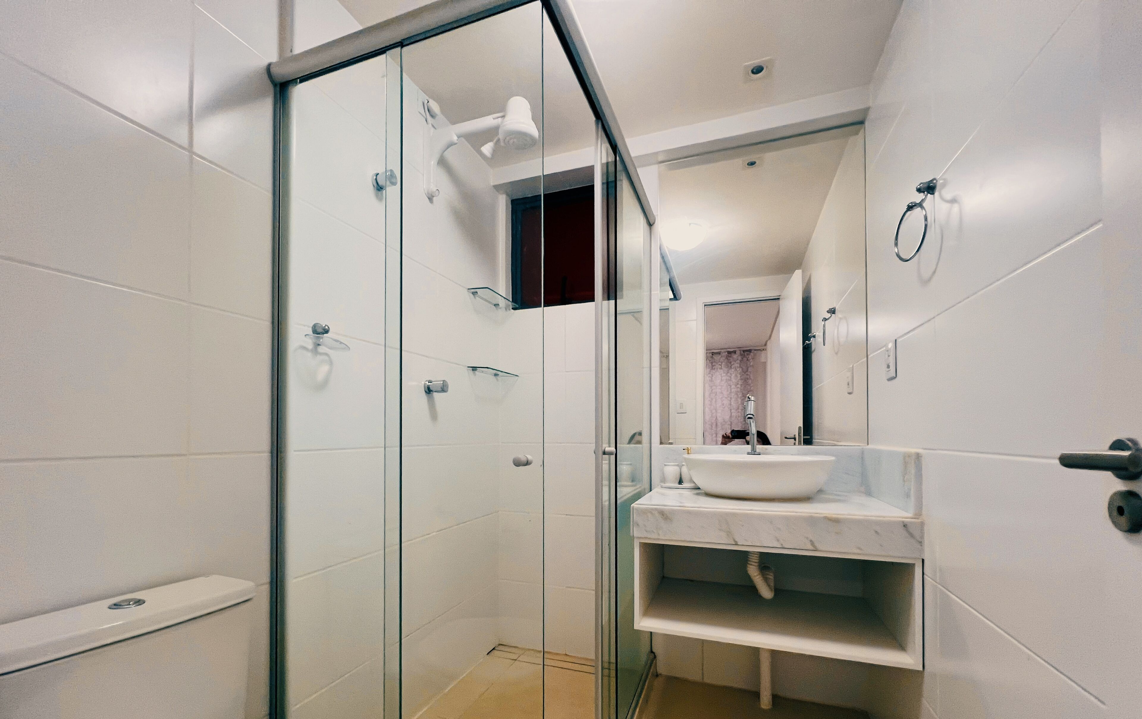 A modern bathroom with a glass shower enclosure, a white sink, and a marble countertop.