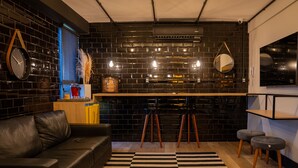 Una sala de estar moderna con una pared de ladrillo negro, un sofá de cuero negro, una mesa de centro de madera y un tapete a rayas negro y blanco.