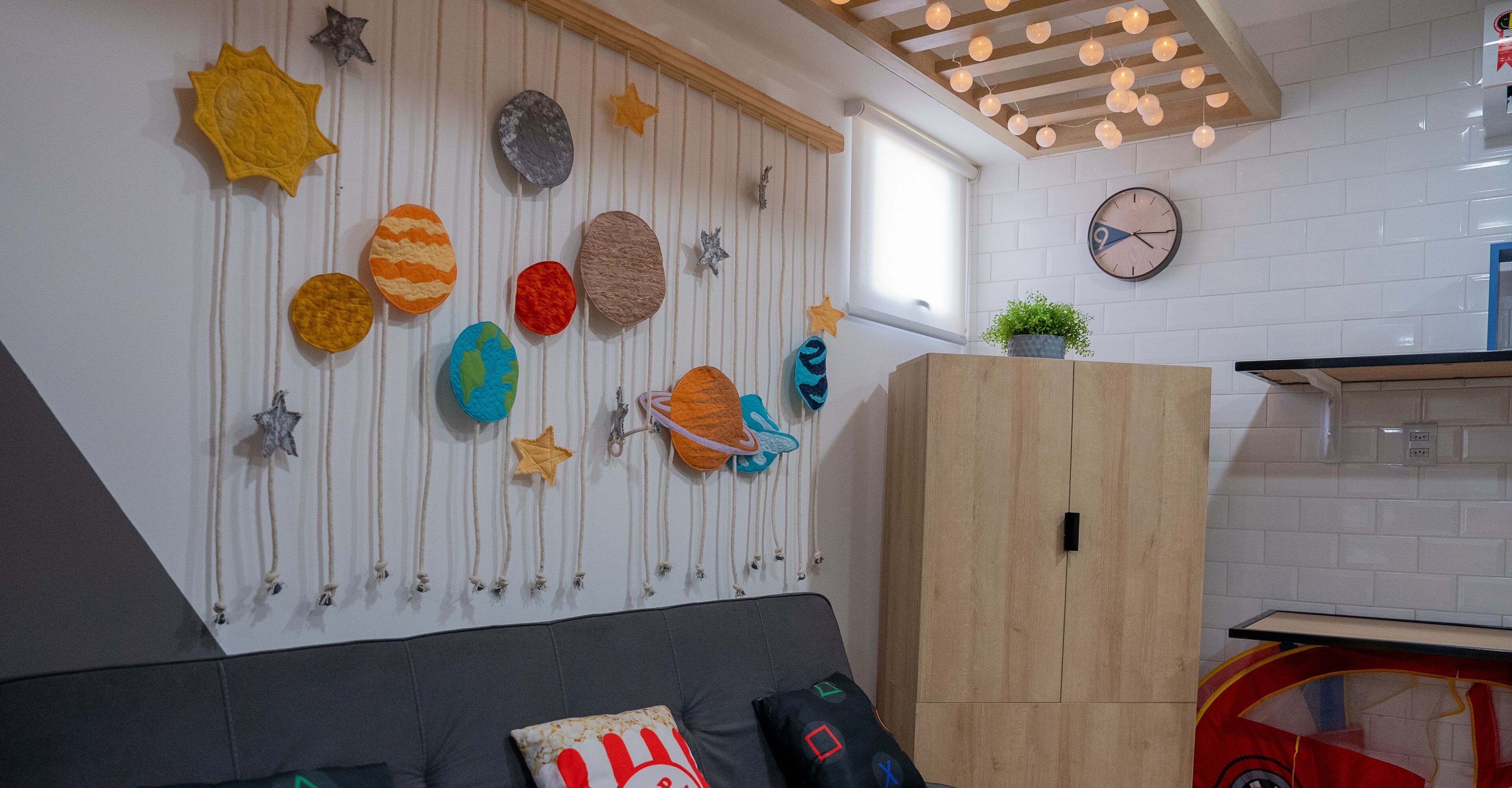 A room with a wall decorated with celestial-themed ornaments, a wooden cabinet, and a clock.