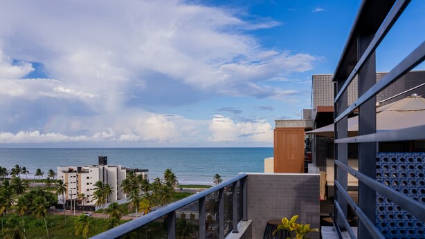 Un edificio moderno con un balcón que da a una playa y al océano.