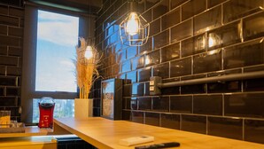 Una cocina moderna con salpicadero de azulejos negros, encimera de madera e iluminación colgante.