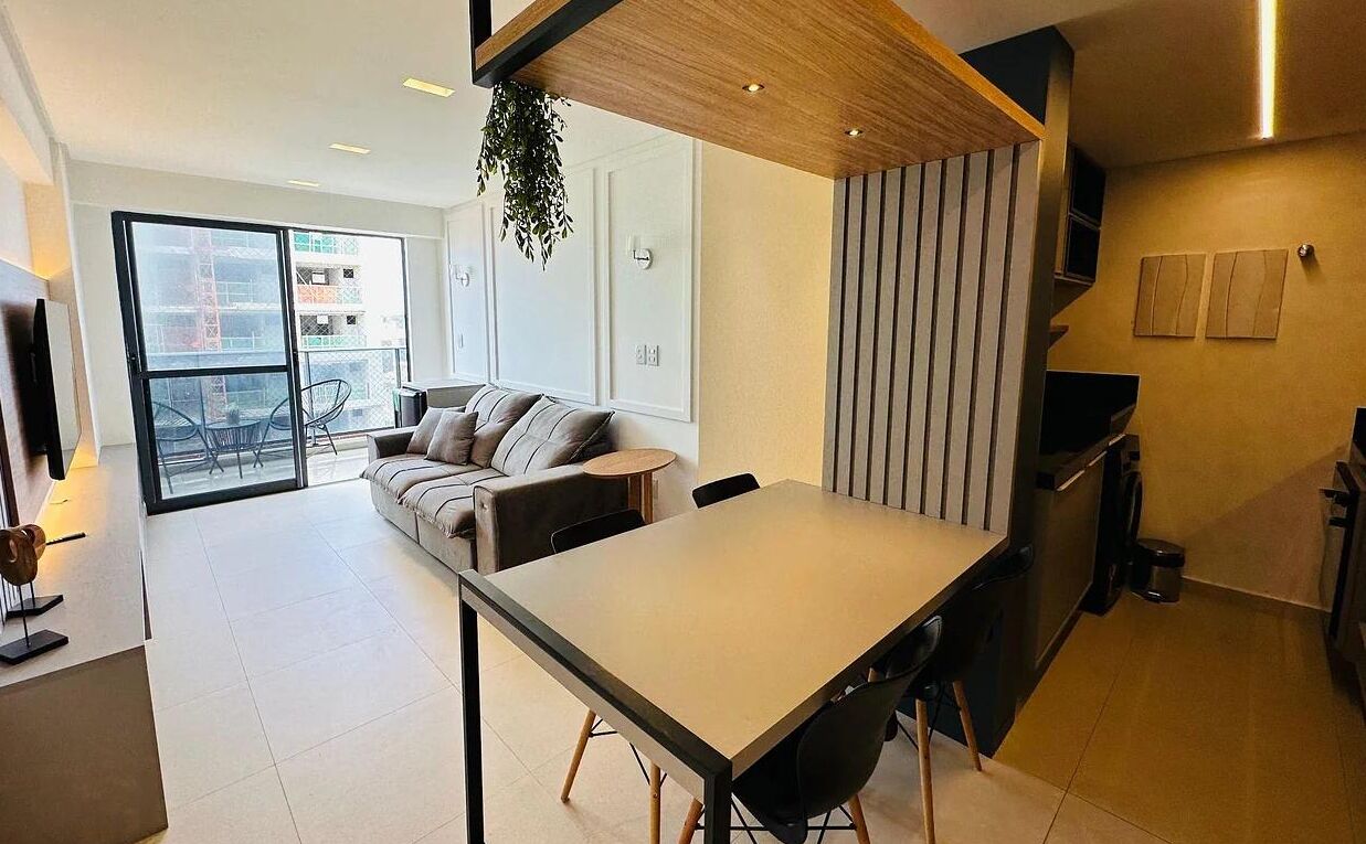 A modern kitchen with a dining area, a sofa, and a large window.