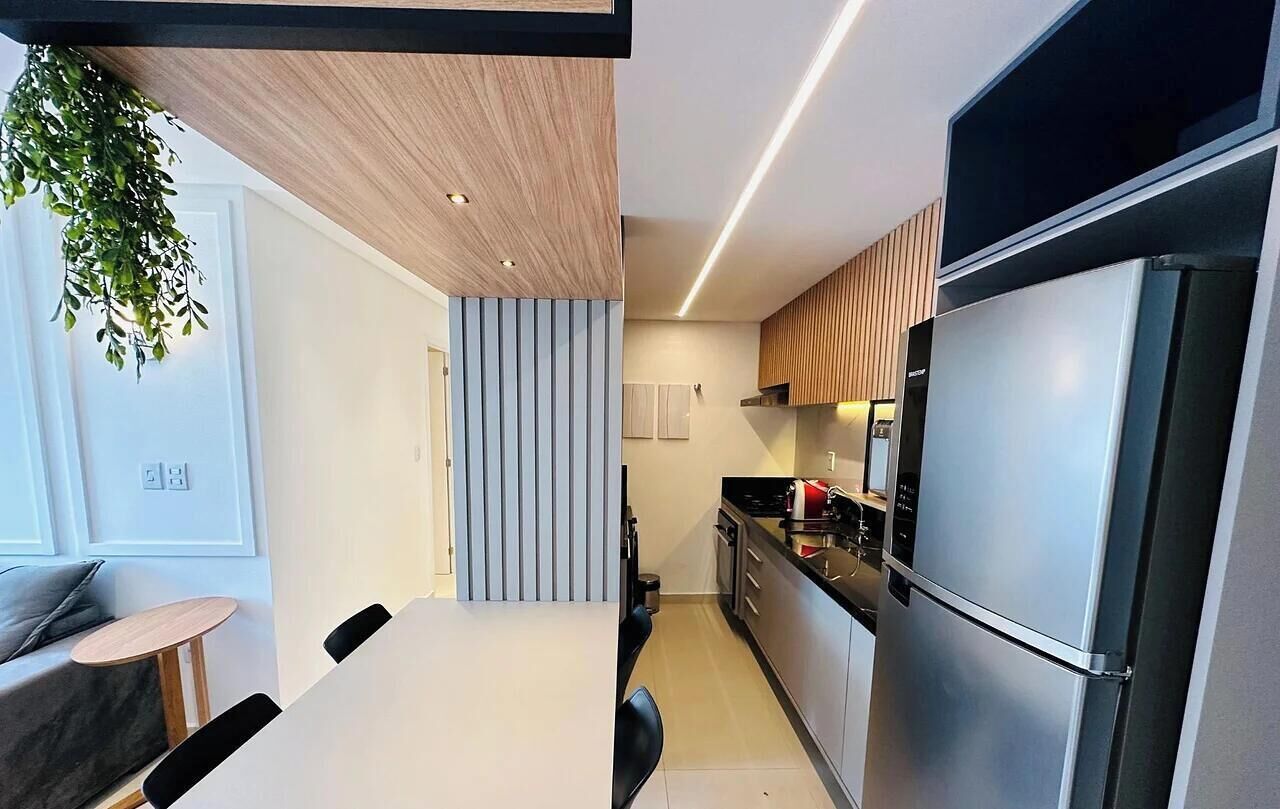 Una cocina moderna con refrigerador de acero inoxidable, paneles de madera y una zona de comedor con una mesa redonda y sillas.