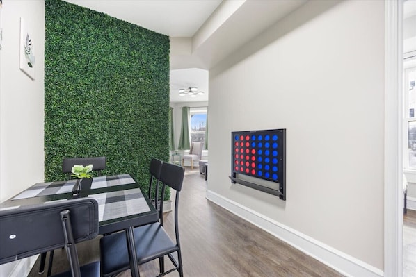 Un coin repas avec un mur vert, une table à carreaux et un jeu de société.