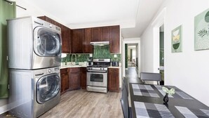 Une cuisine compacte équipée d’un four encastré, d’un évier et d’un lave-linge à double porte.