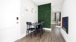 Un espace repas moderne avec un mur vert, une table à manger et quatre chaises.