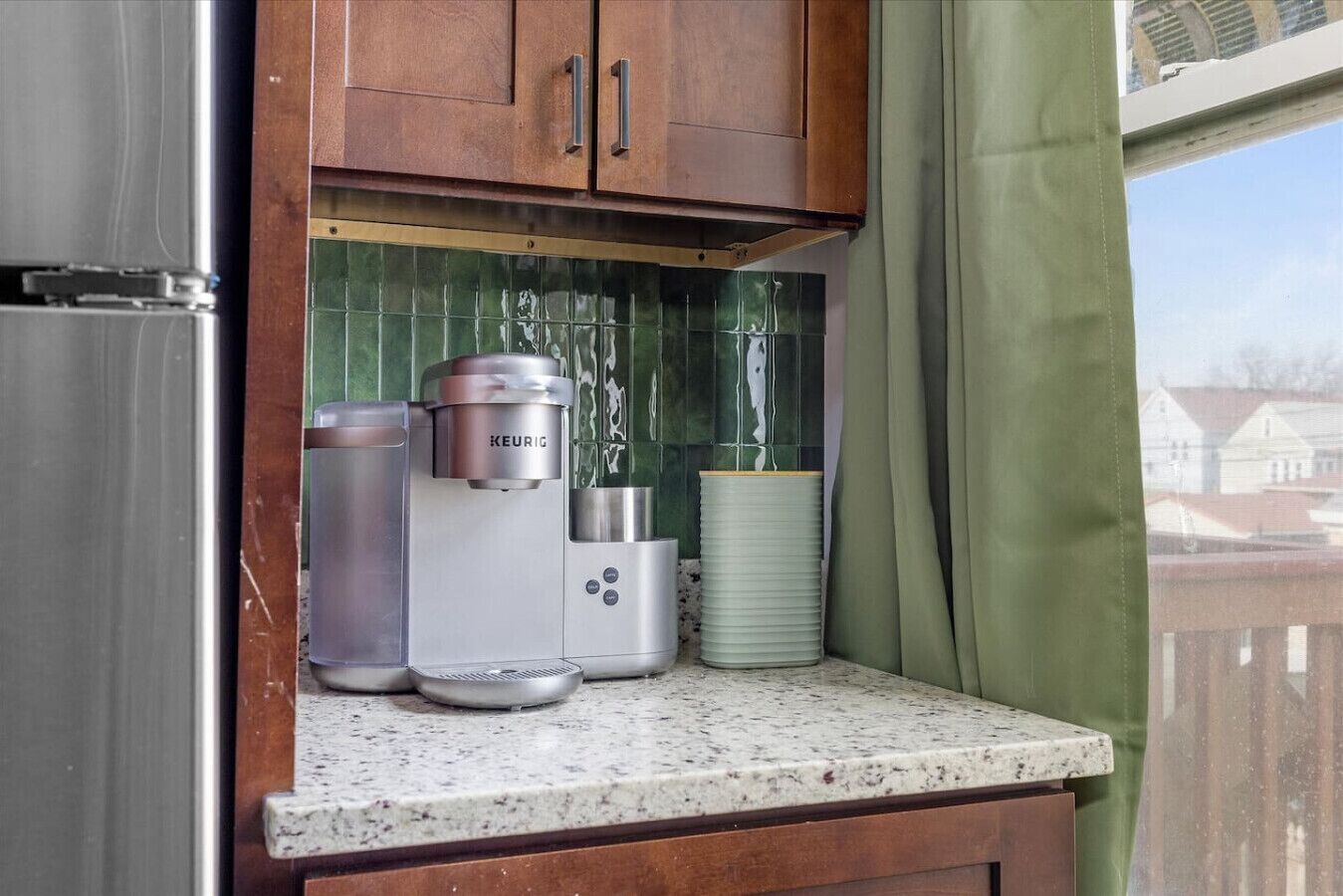 Une petite cuisine équipée d’une machine à café, d’une bouilloire et d’une pile d’assiettes.