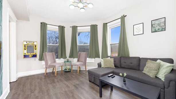Un salon avec un canapé gris, deux fauteuils, une table basse et une petite table d’appoint.