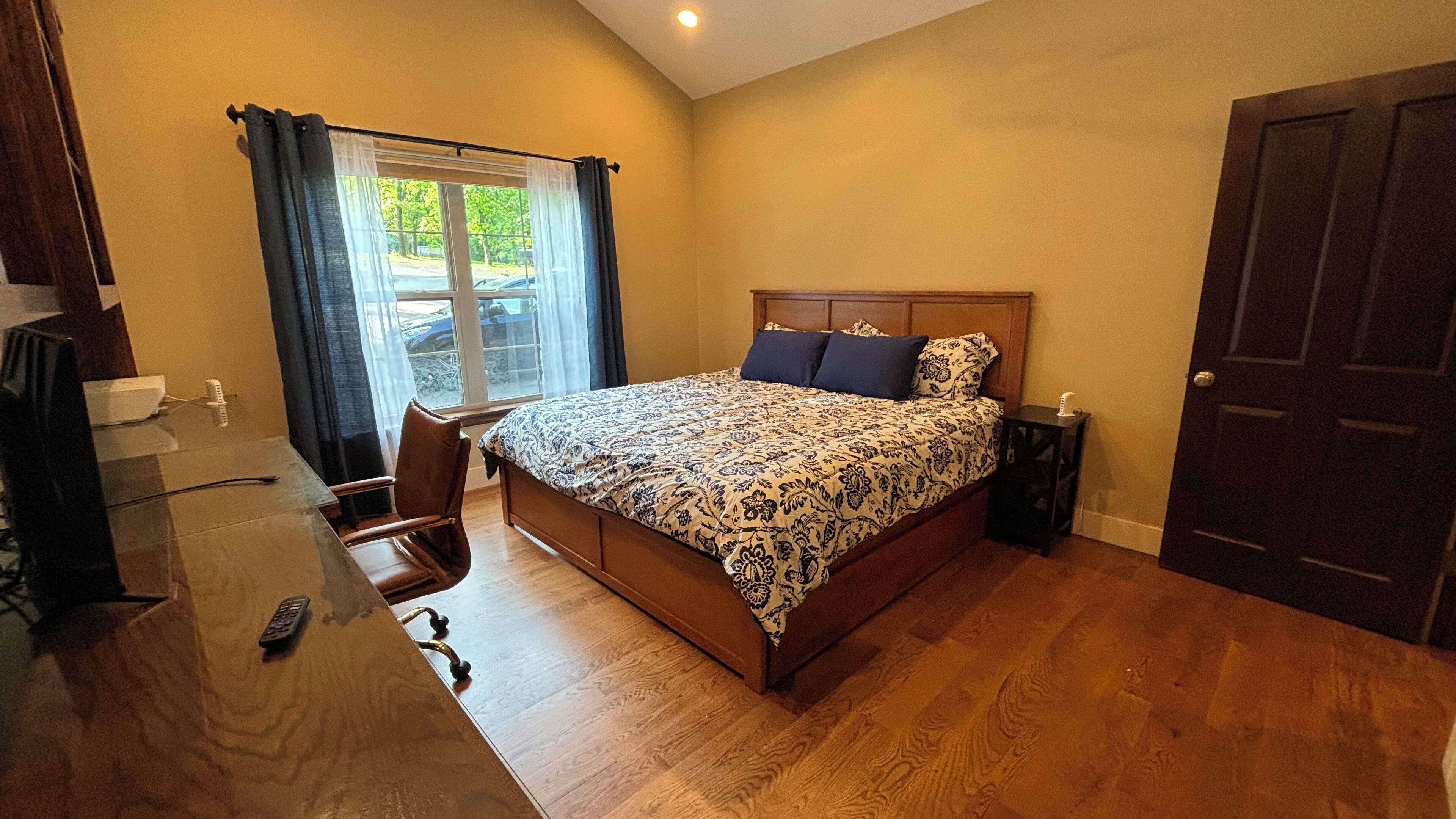 A bedroom with a bed, a desk, and a chair.