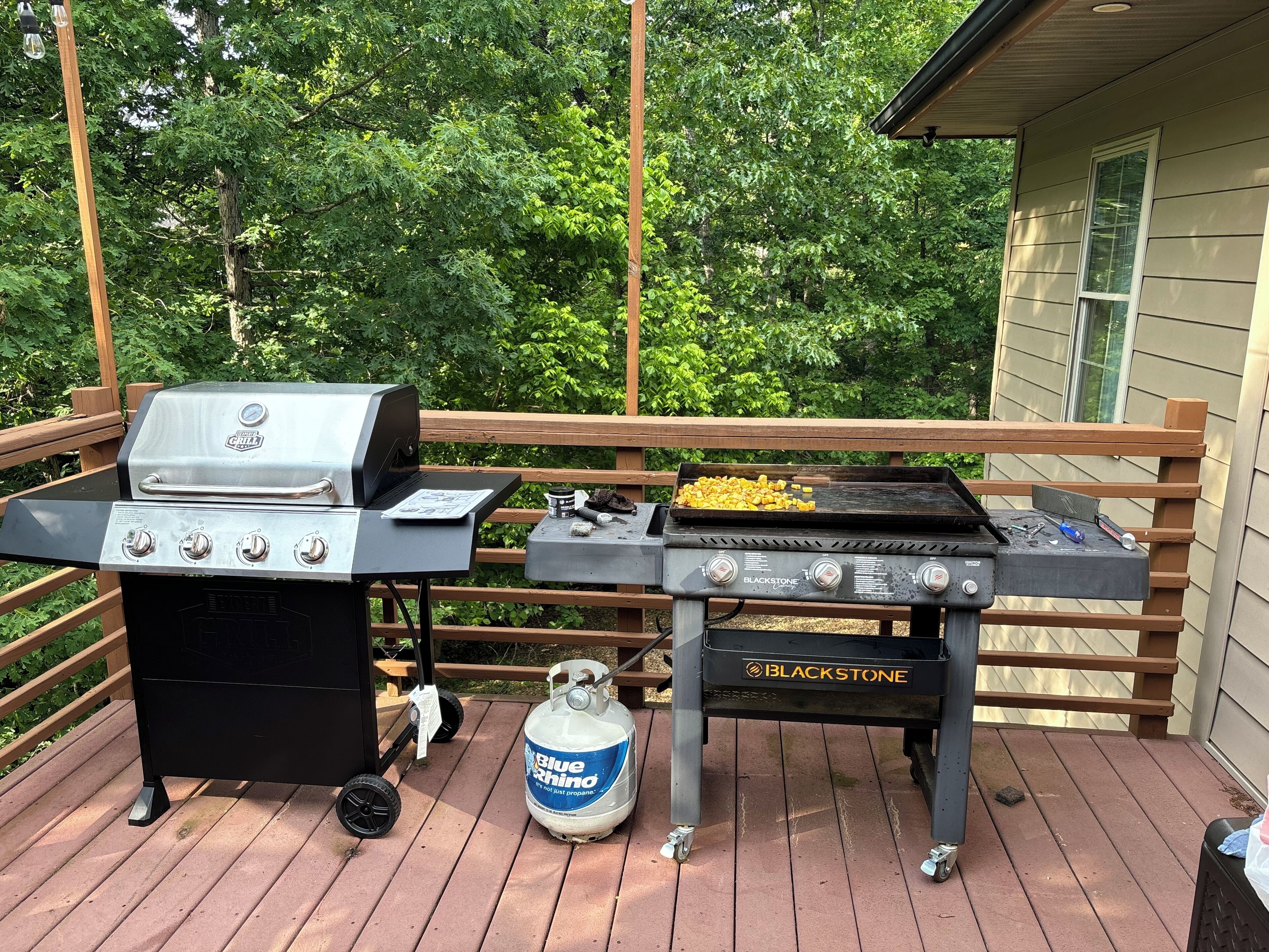A barbecue grill with a propane tank on a wooden deck.