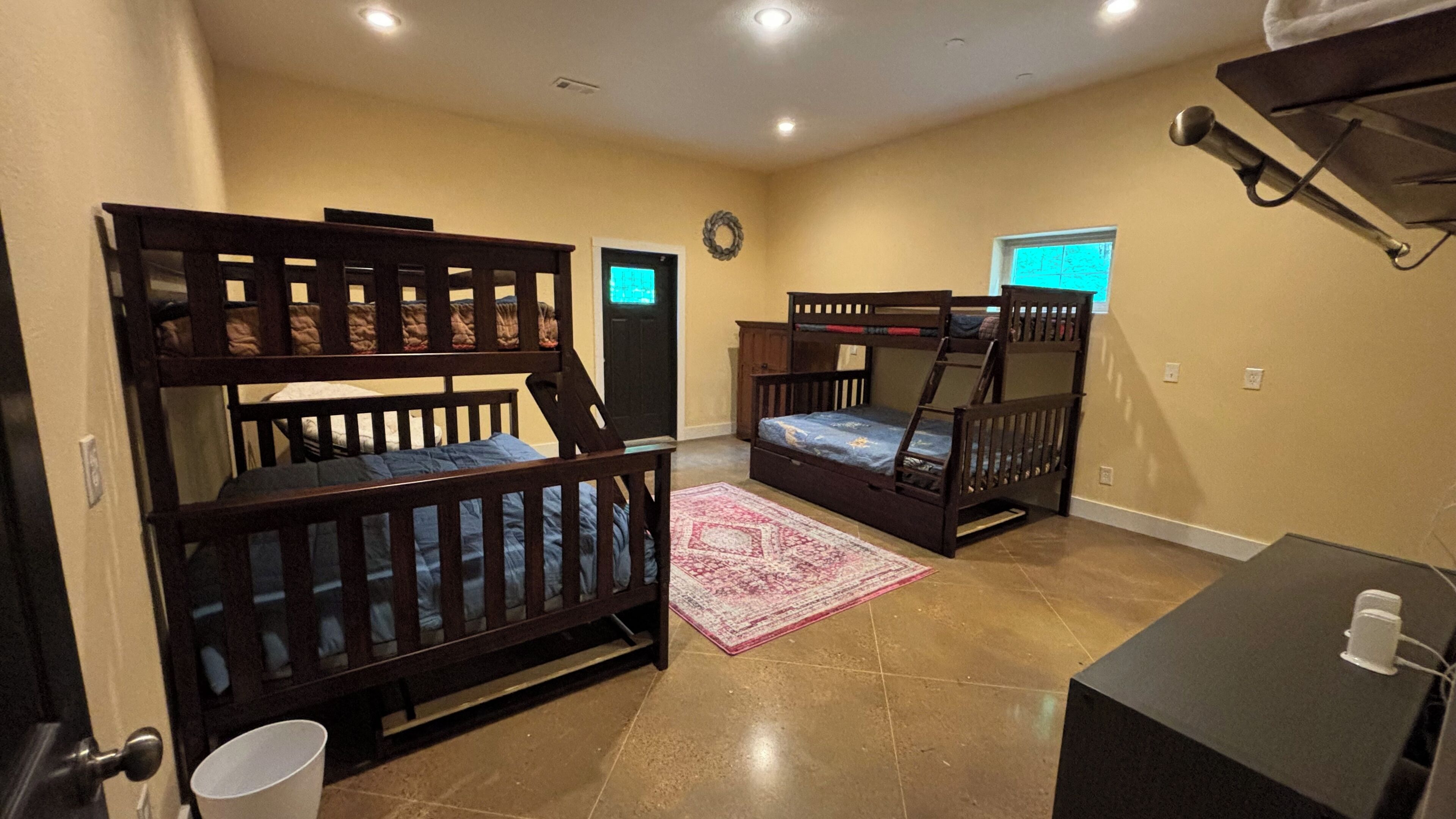 A room with bunk beds, a rug, a desk, and a door.
