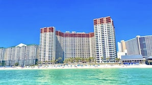 A beachfront hotel with multiple high-rise buildings, a sandy beach, and clear blue water. - Beachfront Resort Condo w/HUGE Lagoona Pool (Panama City Beach)
