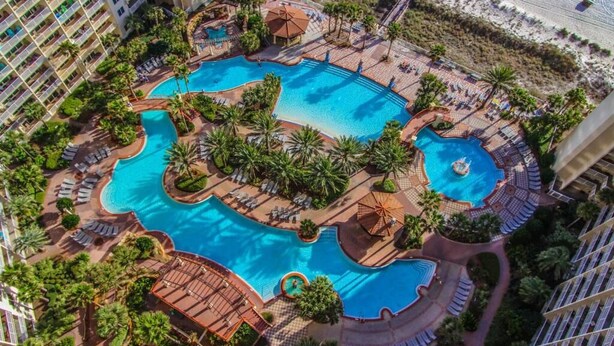 A resort with multiple swimming pools, palm trees, and beach views. - Beachfront Resort Condo w/HUGE Lagoona Pool (Panama City Beach)