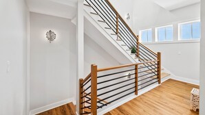 A modern staircase with wooden railings and metal balusters, white walls, and wooden flooring. - The Sea Star: Sugar Sands Gated Community, Private Pool (Mexico Beach)