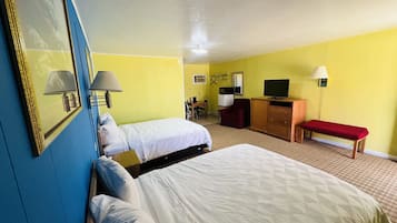 Une chambre d’hôtel avec deux lits, un bureau, une télévision et un banc.