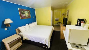 Ein Hotelzimmer mit einem Bett, einem Schreibtisch, einem Stuhl, einer Lampe und einem Fernseher.