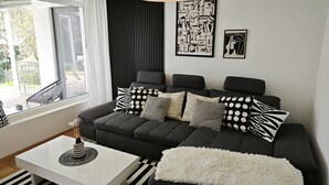 A modern living room with a sectional sofa, a white coffee table, and a black and white striped rug. - 3 Zimmer Ferienwohnung 80 qm (Bamberg)