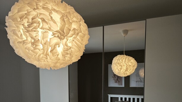 A bedroom with a bed, bedside table, and a chair. There are two hanging light fixtures. - 3 Zimmer Ferienwohnung 80 qm (Bamberg)